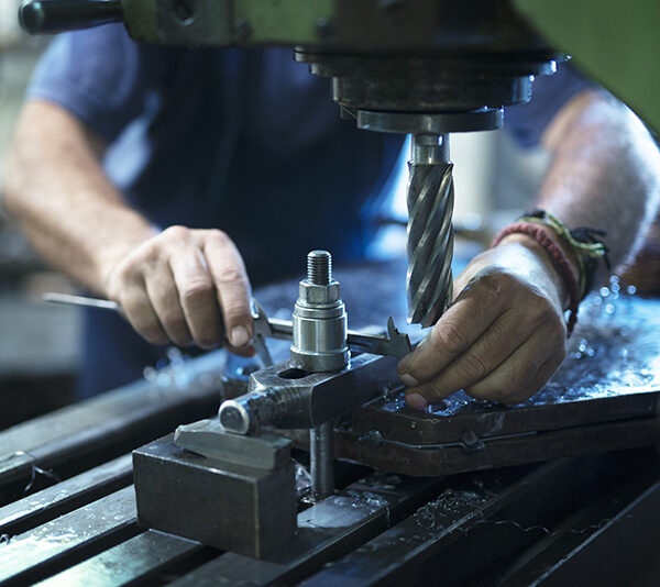 Worker operating industrial machine in metal workshop.